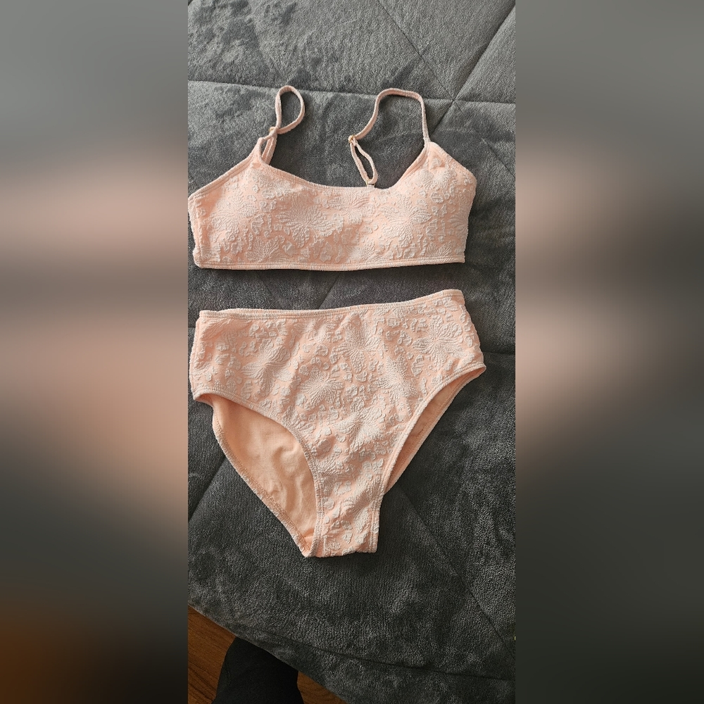 Womens 2 piece bathing suit in soft beaxh with a light floral Hawaiian pattern .